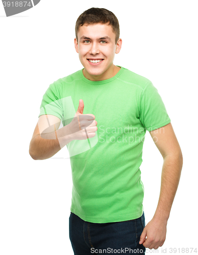 Image of Cheerful young man showing thumb up sign