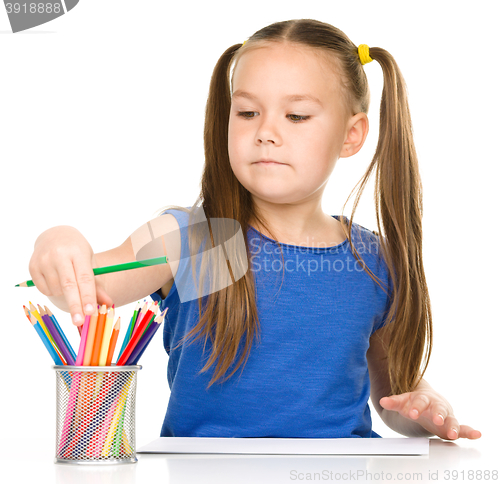 Image of Little girl is drawing using pencils