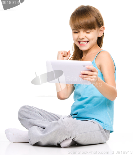 Image of Young girl is playing game using tablet
