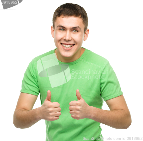 Image of Cheerful young man showing thumb up sign