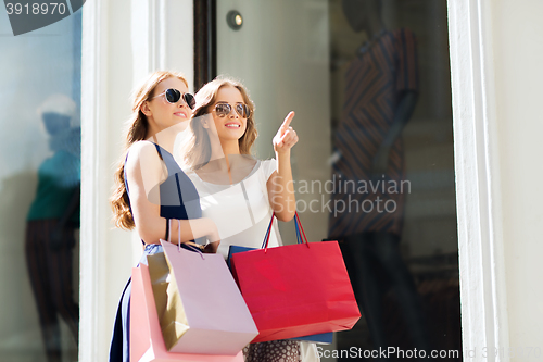 Image of happy women with shopping bags outdoors