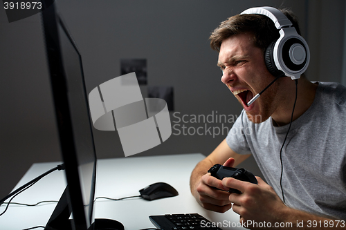 Image of man in headset playing computer video game at home