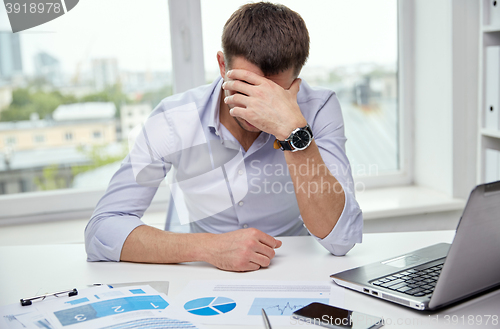 Image of stressed businessman with papers in office