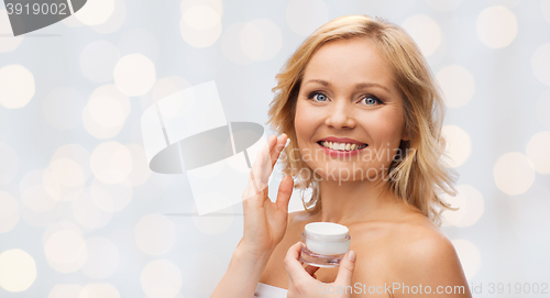 Image of happy woman applying cream to her face