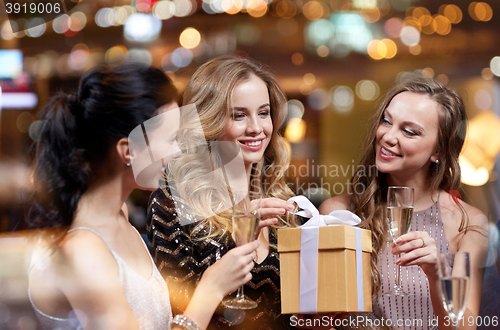 Image of happy women with champagne and gift at night club