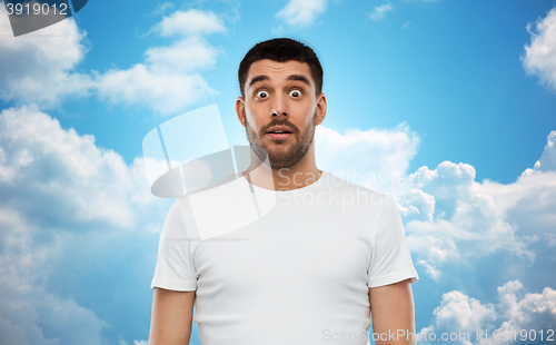 Image of scared man in white t-shirt over sky background