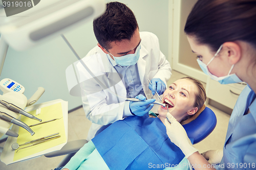 Image of male dentist treating female patient teeth