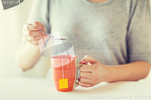 Image of close up of woman adding sugar to tea cup