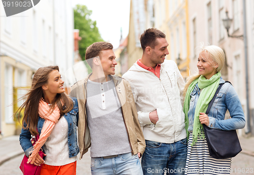 Image of group of smiling friends walking in the city