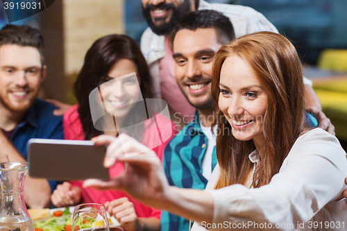 Image of friends taking selfie by smartphone at restaurant
