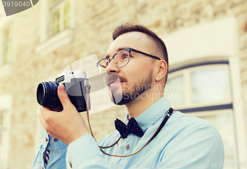 Image of young hipster man with film camera in city