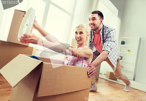 Image of couple with cardboard boxes having fun at new home