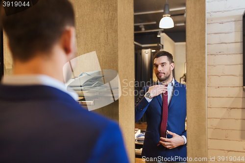 Image of man trying tie on at mirror in clothing store