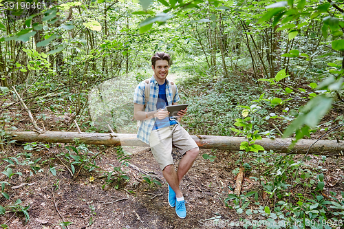 Image of happy man with backpack and tablet pc in woods