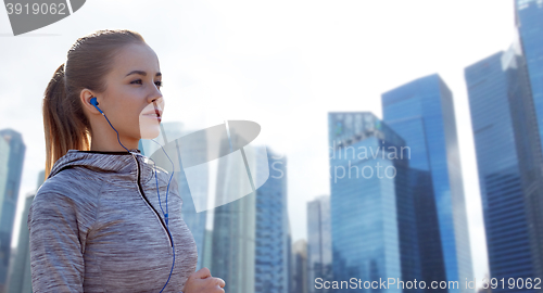 Image of happy woman with earphones running in city