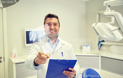 Image of happy dentist pointing to you at dental clinic