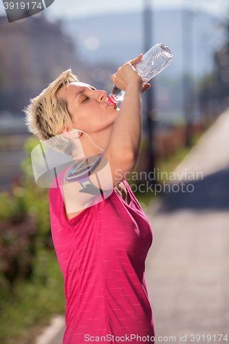 Image of woman drinking  water after  jogging