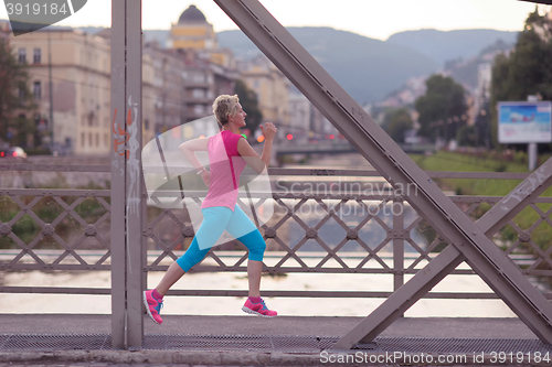 Image of sporty woman running  on sidewalk