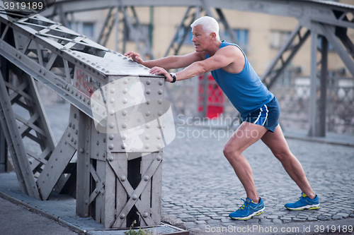 Image of handsome man stretching before jogging