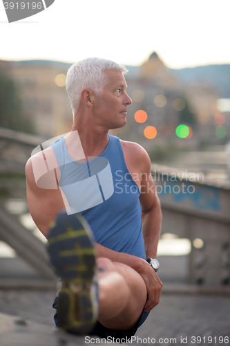 Image of handsome man stretching before jogging