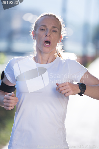 Image of sporty woman running  on sidewalk