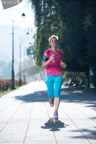 Image of sporty woman running  on sidewalk