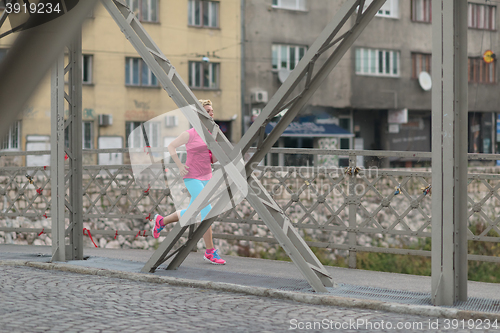 Image of sporty woman running  on sidewalk