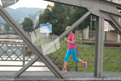 Image of sporty woman running  on sidewalk