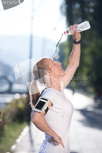 Image of woman drinking  water after  jogging