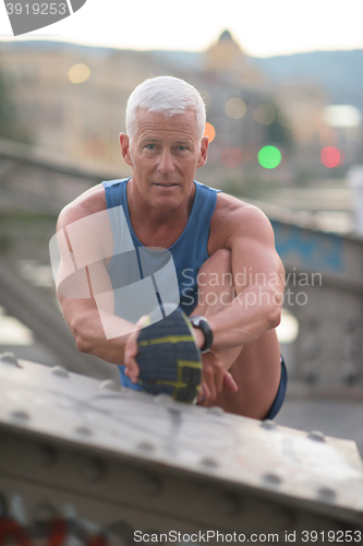 Image of handsome man stretching before jogging