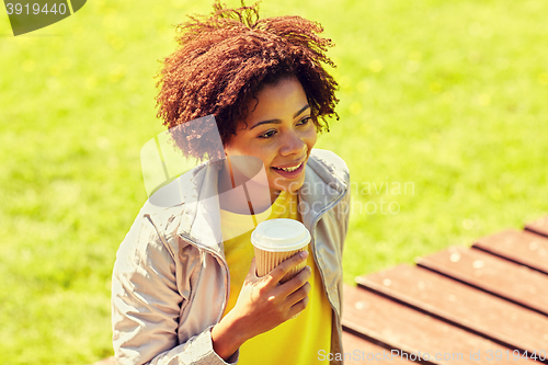 Image of smiling african woman drinking coffee outdoors 