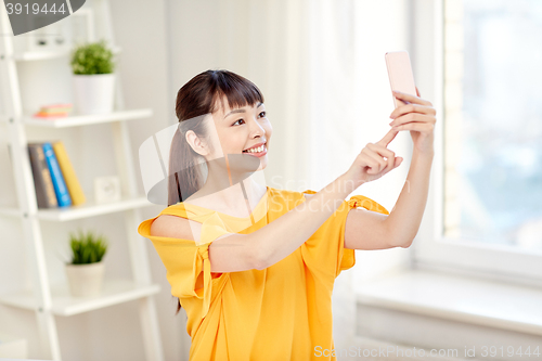 Image of happy asian woman taking selfie with smartphone
