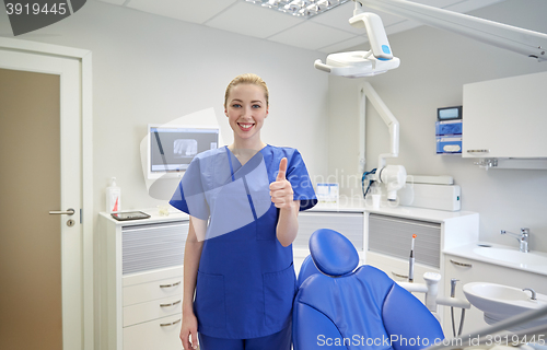 Image of happy female dentist showing thumbs up at clinic