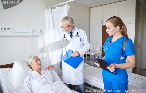 Image of doctor and nurse visiting senior woman at hospital