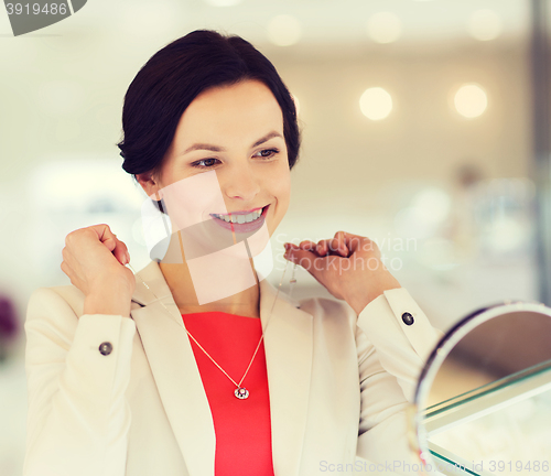 Image of happy woman choosing pendant at jewelry store