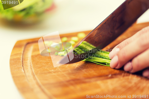 Image of close up of woman chopping green onion with knife