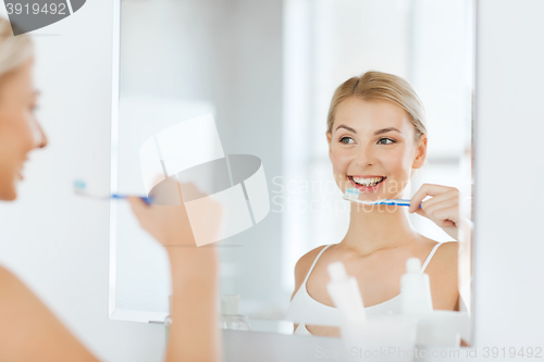 Image of woman with toothbrush cleaning teeth at bathroom