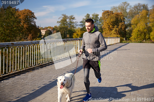 Image of happy man with labrador dog running outdoors