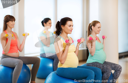 Image of happy pregnant women exercising on fitball in gym