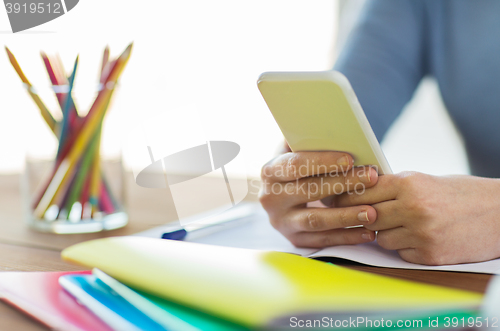 Image of close up of student with smartphone and notebook