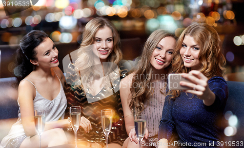 Image of women with champagne taking selfie at night club