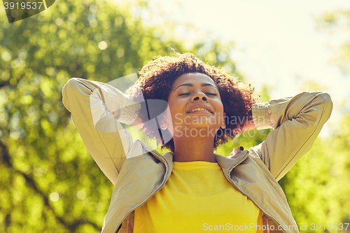 Image of happy african american young woman in summer park