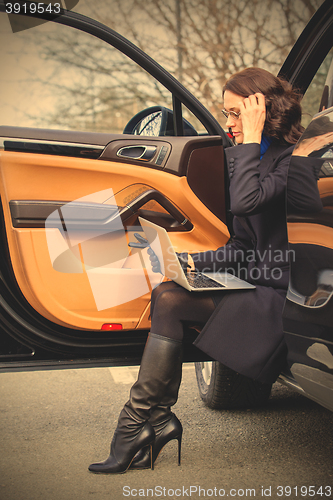 Image of woman sitting on the threshold of the car
