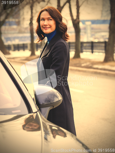 Image of woman in a dark coat near car