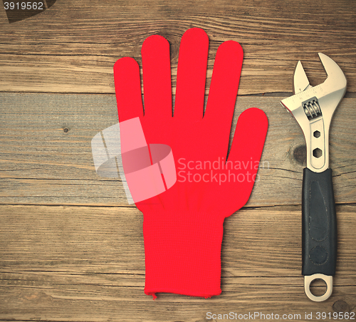 Image of Red protective glove and an adjustable pipe wrench