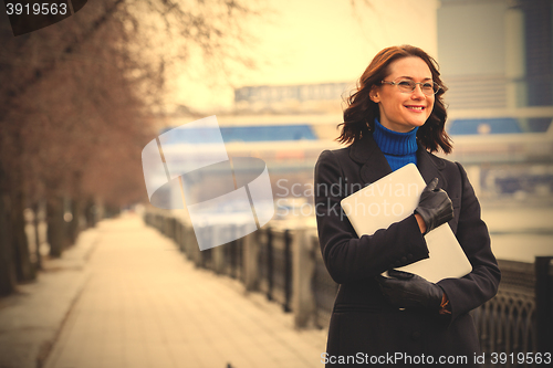 Image of smiling woman with a laptop outdoors