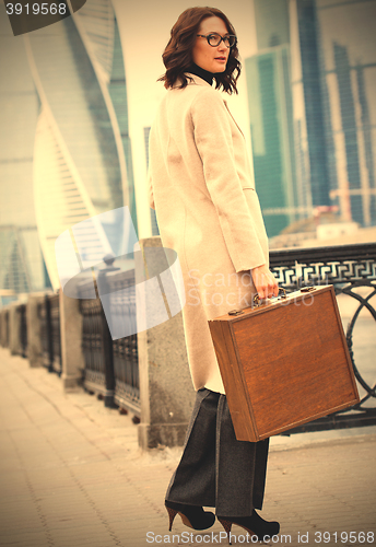 Image of woman in a bright coat and a wooden case