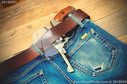 Image of old revolver tucked behind a leather belt