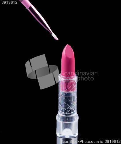 Image of Tube of lipstick with a brush make-up on black 