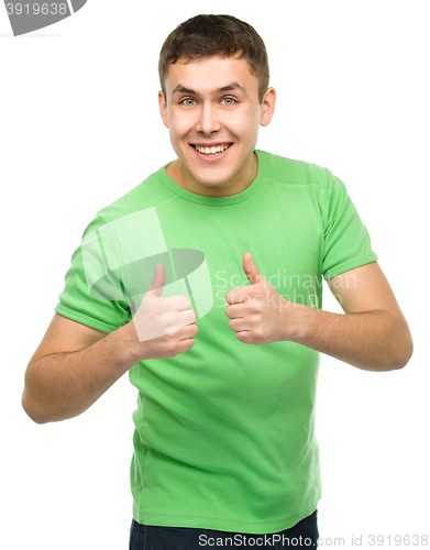 Image of Cheerful young man showing thumb up sign